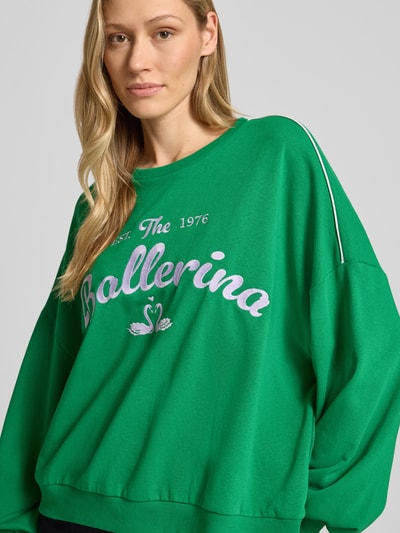 Frauenmodel trägt Oversized Sweatshirt aus Baumwoll-Mix Modell 'JAMIE' von Vero Moda in Grün mit Motiv-Print, Kontraststreifen, Rippenstruktur, Nahaufnahme Oberkörper