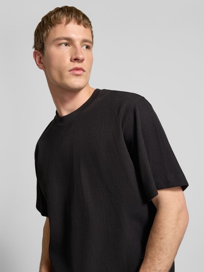 Männermodel trägt T-Shirt mit Ripp-Optik Modell 'HARRISON' von JACK & JONES in Schwarz, Reine Baumwolle, Lockere Passform, Nahaufnahme Oberkörper.