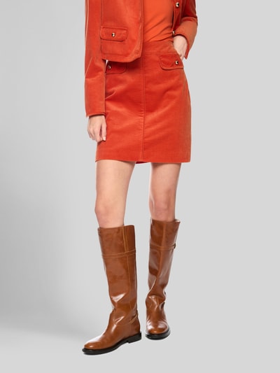 Frauenmodel trägt Minirock aus Cord mit Pattentaschen von Marc Cain in Orange, reine Baumwolle, gerade Form, Nahaufnahme Unterkörper.