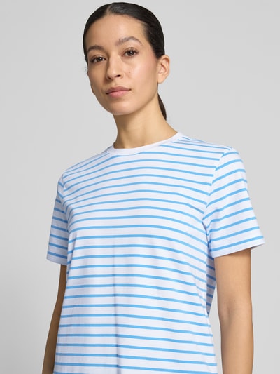 Kobieta prezentuje damski t-shirt T-Shirt mit Rundhalsausschnitt Modell 'NORA' od Vila, mieszanka bawełny z dodatkiem streczu, prosty krój, okrągły dekolt, długość tyłu w rozmiarze S 57 cm, białe tło, niebieskie paski, gładka faktura, zbliżenie na górną część ciała, przód