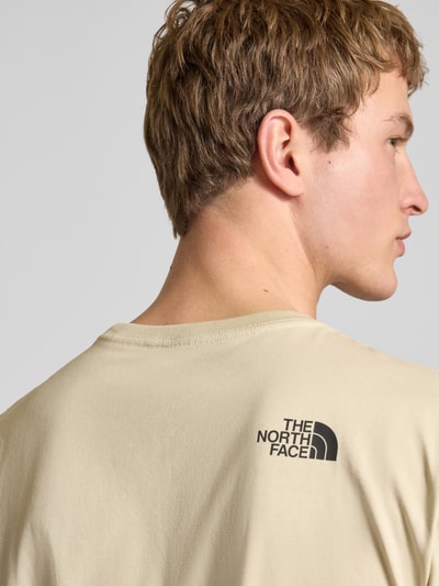 Mannelijk model draagt T-shirt uit katoenmix model 'EVOLUTION' van The North Face, regular fit, labelprint, detailopname schouder.