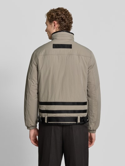 Männermodel trägt Regular Fit Jacke mit aufgesetzten Taschen Modell 'BLOUSON' von Armani Exchange in Beige mit schwarzen Details, Ganzkörperansicht Rückansicht. Rückenlänge 69 cm, Schulterbreite 43 cm, Brustweite 48 cm, Ärmellänge 64 cm.