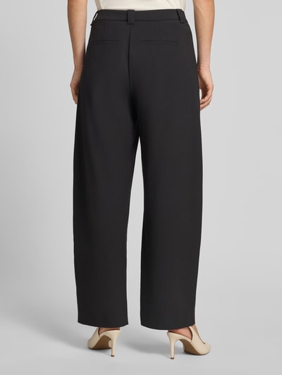 Vrouwenmodel draagt Barrel Fit broek met achterzakken model 'UNPACK' van DRYKORN, materiaalmix met viscose, zwarte kleur, volledig zicht van achteren.