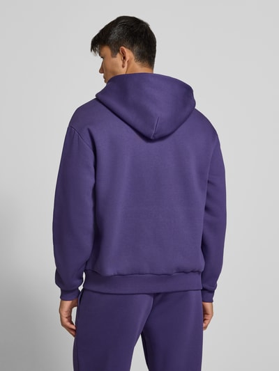 Männermodel trägt Relaxed Fit Sweatjacke aus Baumwoll-Mix mit Label-Detail von REVIEW in Lila, glatte Textur, Ganzkörperansicht Rückansicht.