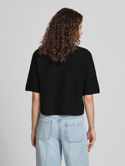 Frauenmodel trägt Boxy Fit Strickjacke aus Rippstrick Modell 'SILLY' von PIECES, Melange-Optik, kurzarm, Rückansicht, Ganzkörperansicht.