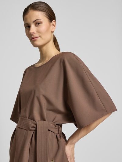 Vrouwenmodel draagt Relaxed Fit blouse uit viscosemix model 'Rikas' van MOS MOSH in bruin, met stoffen band, halflange mouwen, ronde hals, ruglengte maat S 63 cm, mouwlengte 28 cm, halflange mouwen, close-up bovenlichaam vooraanzicht.