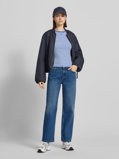 Frauenmodel trägt Straight Leg Jeans aus Baumwoll-Mix Modell 'SOPHIE' von Tommy Jeans in klassischer Denim-Optik mit Logo-Stitching, 5-Pocket-Design und Knopf-Reißverschluss, Ganzkörperansicht von vorne.