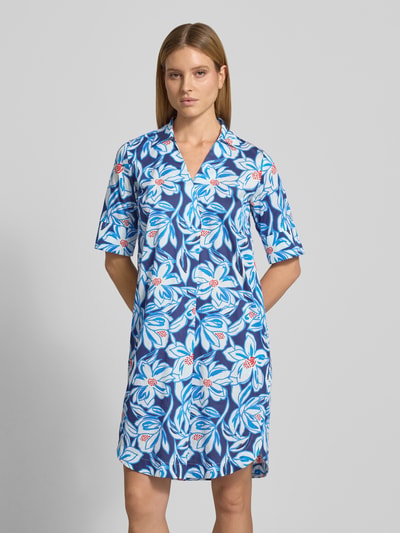 Frauenmodel trägt Knielanges Hemdblusenkleid im Allover-Look von WHITE LABEL aus Reiner Baumwolle, Gerader-Schnitt, Hemdblusenkragen, V-Ausschnitt, 1/2-Arm, Knielänge, Allover-Look mit floralen Motiven, Farben Blau, Weiß, Rot, glatte Textur, Ganzkörperansicht von vorne.