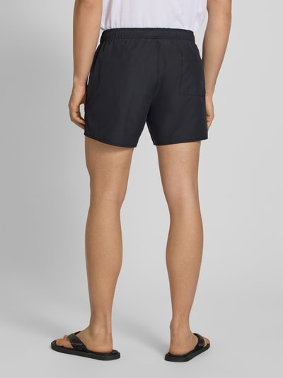 Männermodel trägt Badeshorts mit Motiv-Print von Hugo Blue, effen kleuren look, motiefprint, elastisch boord, popeline, achterzak, steekzakken, Ganzkörperansicht Rückansicht