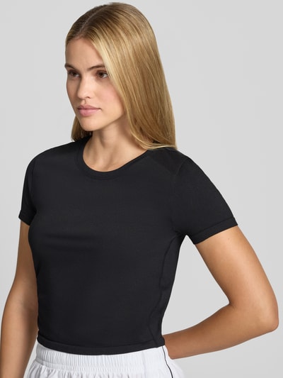 Kobiece modelka nosi damski t-shirt Fabletics Cropped T-Shirt mit Rundhalsausschnitt Modell 'Feather' z elastycznej mieszanki materiałów, krój krótki, okrągły dekolt, długość tyłu w rozmiarze S: 45 cm, widok na górną część ciała z przodu.