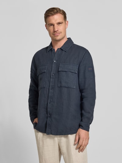 Męski model nosi Relaxed Fit Freizeithemd aus reinem Leinen Modell 'LOCKY' von BOSS Orange, ciemnoniebieska, lniana, jednokolorowa koszula z długimi rękawami, naszywanymi kieszeniami, naszywką z logo, widok z przodu na całe ciało.