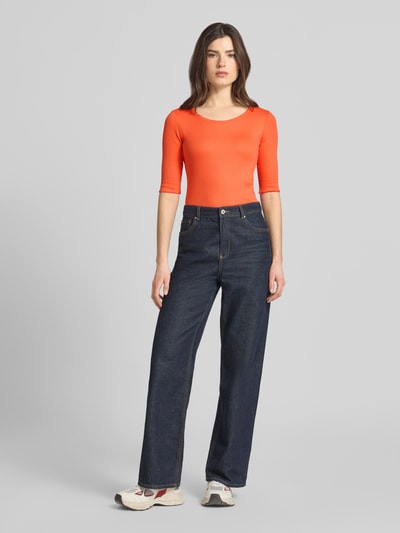 Frauenmodel trägt T-Shirt mit Label-Applikation von Marc Cain in Orange, körpernah geschnitten, U-Ausschnitt, Nahaufnahme Ganzkörperansicht von vorne.
