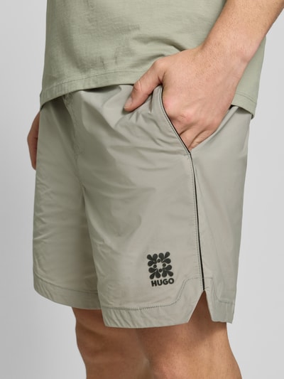 Männermodel trägt Regular Fit Shorts mit Label-Applikation Modell 'COLAS262S' von HUGO, Optik: Unifarben, Nahaufnahme Oberschenkel.