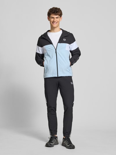 Männermodel trägt schwarze Sweatpants mit Logo-Stitching Modell 'CASPIO' von SERGIO TACCHINI, Material-Mix mit Stretch-Anteil, körpernaher-Schnitt, elastischer Bund mit Kordelzug, seitliche Eingrifftaschen, elastische Abschlüsse, Innenbeinlänge bei Größe M 78 cm, Ganzkörperansicht von vorne.