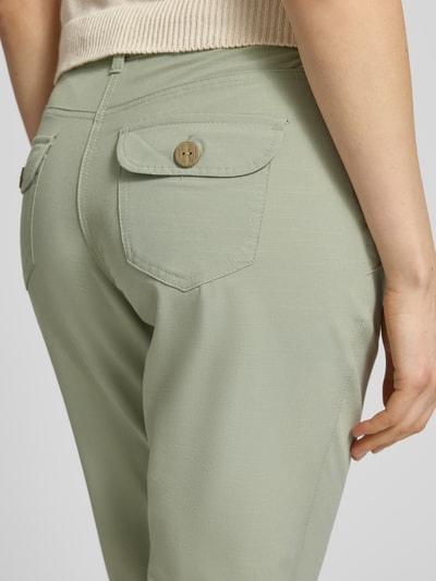 Kobiece modelka nosi bermudy z wpuszczanymi kieszeniami 'Bermudas mit Gürtel und Eingrifftaschen' od G.I.G.A. DX, mieszanka bawełny z dodatkiem streczu, dopasowany krój, zapięcie na guzik i zamek błyskawiczny, pasek z efektem plecionki, wpuszczane kieszenie, kieszenie z tyłu, szerokość w rozmiarze 36: 40 cm, długość wewnętrzna nogawki w rozmiarze 36: 46 cm; zbliżenie na tył.