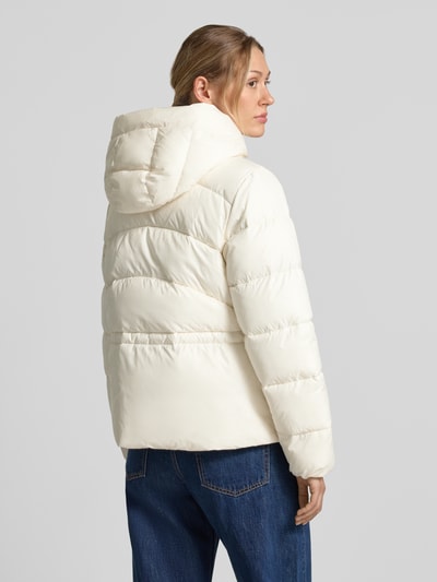 Frauenmodel trägt Regular Fit Jacke mit Kapuze Modell 'Pepulina' von BOSS in creme, unifarben, mit Tunnelzug, Reißverschluss und Logo-Patch, Material mit glatter, wattierter Oberfläche, Ganzkörperansicht Rückansicht.
