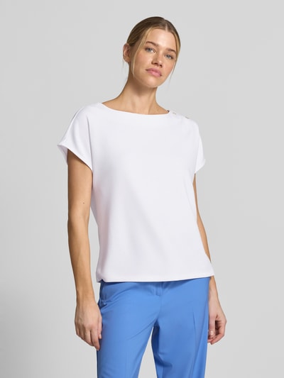 Frauenmodel trägt T-Shirt mit Zierknöpfen und Rundhalsausschnitt von Comma, Viskose-Mix mit Stretch-Anteil, Relaxed-Fit, weiße Farbe, Ganzkörperansicht von vorne.