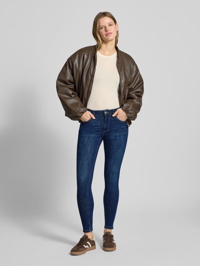 Frauenmodel trägt Slim Fit Jeans im 5-Pocket-Design von Review aus elastischem Baumwoll-Mix in Dunkelblau, Ganzkörperansicht von vorne.