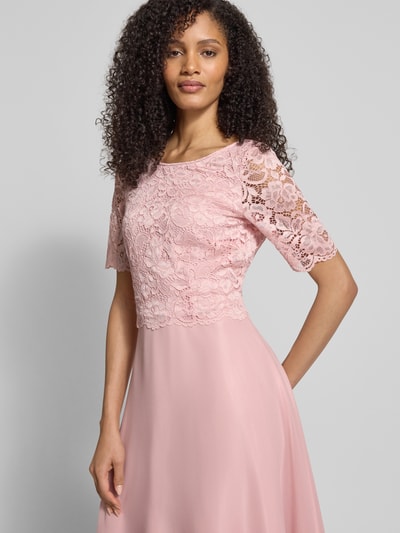 Frauenmodel trägt Cocktailkleid mit Spitzenbesatz von Vera Mont im Unifarbenes-Design, Material-Mix mit Stretch-Anteil, Nahaufnahme Oberkörper.