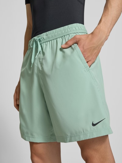 Mannenmodel draagt Shorts met Logo-Print en Steekzakken van NIKE TRAINING, mintkleur, elastische tailleband, straight fit, zijzakken, vooraanzicht close-up.