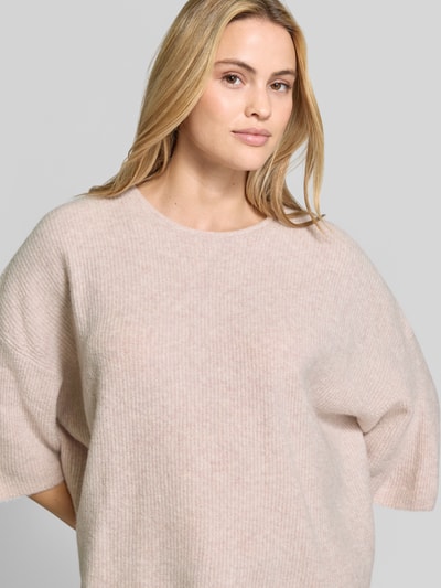 Vrouwenmodel draagt Oversized Strickpullover mit Leinen-Anteil van American Vintage in licht beige, Materiaalmix met linnen, ronde hals, oversized fit, halflange mouwen, geribd, ruglengte maat XS/S 50 cm, mouwlengte 54 cm, nahaufnahme bovenlichaam.