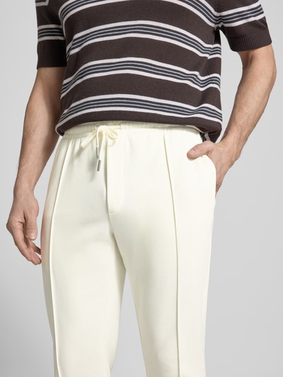 Męski model nosi Regular Fit Hose mit elastischem Bund von Antony Morato, mieszanka bawełny, jasny kolor, długość wewnętrzna nogawki 76 cm, szerokość w rozmiarze M 41 cm, szwy pionowe, pas elastyczny, zdjęcie w zbliżeniu na górną część spodni.