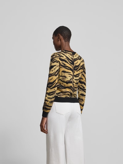 Frauenmodel trägt Strickjacke mit Viskose- und Woll-Anteil von Kenzo, gelb-schwarzes Tiger-Muster, kombiniert mit weißen Hosen, Ganzkörperansicht Rückansicht. Damen Strickjacke, Material-Mix, Slim Fit, Rundhalsausschnitt, Knopfleiste, Langarm, Rückenlänge S: 51 cm.
