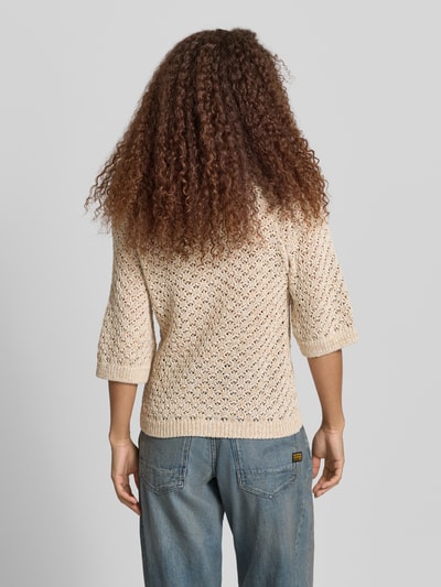 Männermodel trägt Boxy Fit Strickpullover aus Baumwoll-Mix Modell 'AMBER' von Pepe Jeans, kremowy, imitacja dzianiny, faktura, aplikacja z metką, krótki rękaw, ażur, widoczne wykończenie prążkowane, Ganzkörperansicht Rückansicht.
