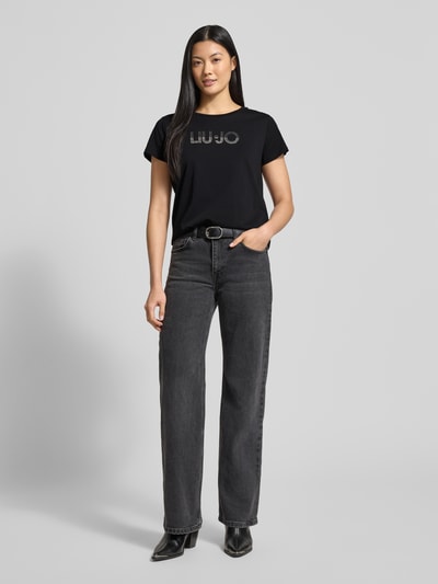 Frauenmodel trägt T-Shirt mit Rundhalsausschnitt und Ziersteinbesatz von LIU JO SPORT aus reiner Baumwolle, Regular-Fit, Ganzkörperansicht von vorne.