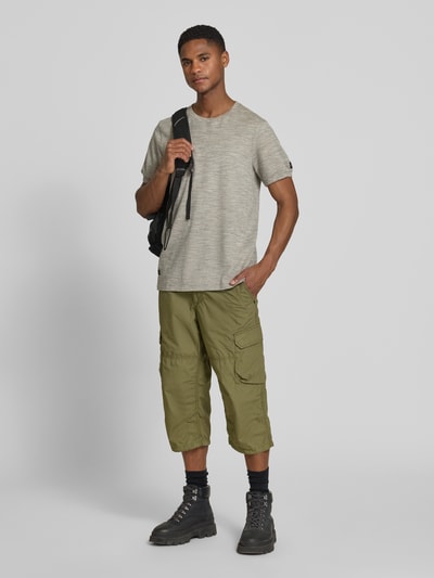 Męski model nosi Regular Fit Capri-Bermudas mit Cargotaschen von camel active z bawełny, detal z logo, oliwkowy odcień, Ganzkörperansicht von vorne.