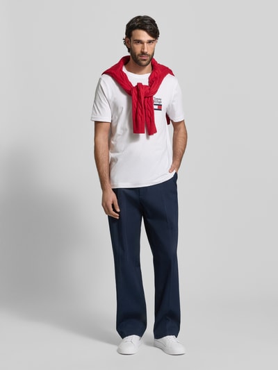 Männermodel trägt Regular Fit T-Shirt aus reiner Baumwolle Modell 'BRAND LOVE TEXT' von Tommy Hilfiger, Optik: Unifarben, Label-Stitching, Logo-Stitching, Rundhals, Kurzarm, Ganzkörperansicht von vorne.