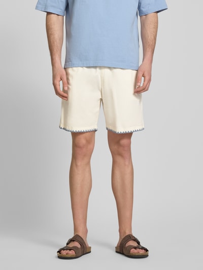 Männermodel trägt Shorts mit umstochener Kante von REVIEW in Cremeweiß, Baumwoll-Mix, elastischer Bund, seitliche Taschen, Ganzkörperansicht von vorne.
