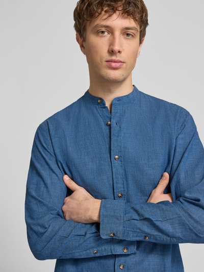 Männermodel trägt Regular Fit Freizeithemd aus Baumwoll-Leinen-Mix von Jack & Jones in Blau mit Stehkragen, Knopfleiste, Nahaufnahme Oberkörper.