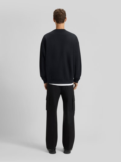 Männermodel trägt Oversized Sweatshirt aus reiner Baumwolle Modell 'DINEX' von HUGO in Unifarben, gerippte Abschlüsse, Ganzkörperansicht Rückansicht.