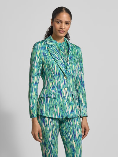 Frauenmodel trägt Slim Fit Blazer im Allover-Look von Marc Cain aus Material-Mix mit Stretch-Anteil, Reverskragen, Knopfverschluss, Pattentaschen, in leuchtenden Grün- und Blautönen mit abstraktem Muster, Ganzkörperansicht von vorne.