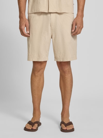 Männermodel trägt Relaxed Fit Stoffshorts aus einer Baumwolle von s.Oliver RED LABEL in Beige, leicht strukturierte Oberfläche, Nahaufnahme Oberschenkel, Ganzkörperansicht von vorne.
