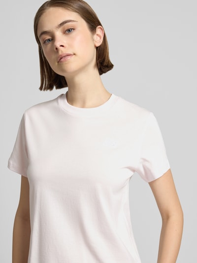 Frauenmodel trägt T-Shirt mit Label-Stitching und Rundhalsausschnitt von New Balance aus reiner Baumwolle im Regular-Fit, Nahaufnahme Oberkörper. Rückenlänge bei Größe S: 56 cm.