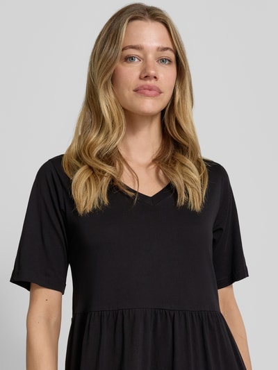 Frauenmodel trägt schwarzes Midikleid mit Smok-Detail, Rundhalsausschnitt, A-Linie aus Reine Baumwolle, Modell 'DERBY' von Soyaconcept, Nahaufnahme Oberkörper. Rückenlänge bei Größe S: 117 cm, Brustweite: 44 cm, Ärmellänge: 27 cm.