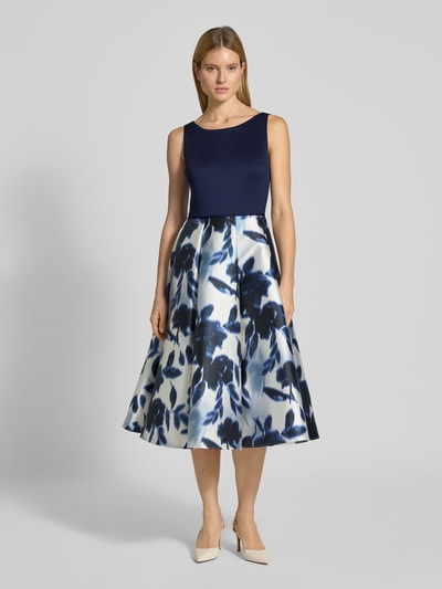 Frauenmodel trägt Cocktailkleid mit Rundhalsausschnitt von SWING in Satin, A-Linie, Midikleid, florales Muster, Ganzkörperansicht von vorne.