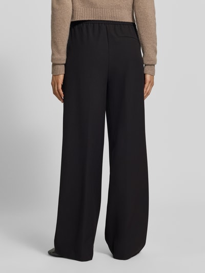 Frauenmodel trägt Wide Fit Sweatpants mit Viskose-Anteil von MYON, schwarze Farbe, elastischer Bund, weiche Textur, Ganzkörperansicht Rückansicht.
