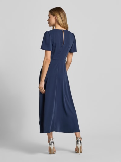 Frauenmodel trägt Cocktailkleid mit V-Ausschnitt von Christian Berg Cocktail in Dunkelblau, A-Linie, Midikleid, Ganzkörperansicht Rückansicht
