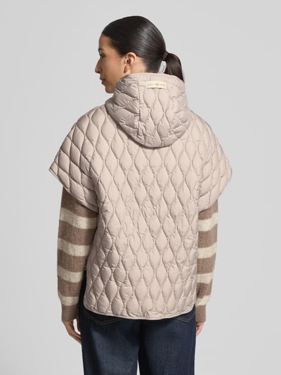 Frauenmodel trägt Steppjacke im kurzärmeligen Design von Fuchs Schmitt in Beige mit Kapuze, lockerer Schnitt, strukturierte Oberfläche, Ganzkörperansicht Rückansicht.