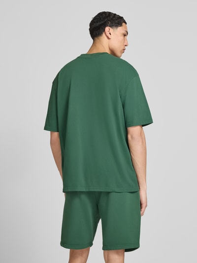 Męski model nosi Oversized T-Shirt mit Logo-Stitching von Pegador, zielony, bawełna, krój oversized fit, okrągły dekolt, długość tyłu w rozmiarze M: 73 cm, całkowita sylwetka z tyłu.