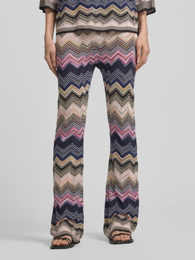 Frauenmodel trägt Flared Hose aus Viskose-Mix im Allover-Look von Oui mit elastischem Bund, geometrischem Muster in Rosa, Beige und Dunkelblau; Nahaufnahme Unterkörper, Vorderansicht.