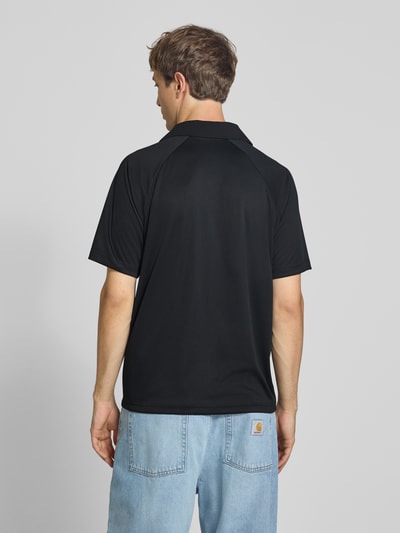 Männermodel trägt Relaxed Fit Poloshirt mit Logo-Stitching von Champion in zwart, Polokraag, met korte mouwen, effen design, Ruglengte bij maat M: 70 cm, Ganzkörperansicht Rückansicht.