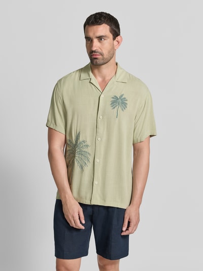 Männermodel trägt Relaxed Fit Freizeithemd aus Viskose mit Stitchings von JACK & JONES, grüner Stoff, Palmenprint, Nahaufnahme Oberkörper. Rückenlänge 70 cm, Schulterbreite 49 cm, Ärmellänge 24 cm, Reverskragen, Knopfleiste, Modell LAFRED PLACEMENT.