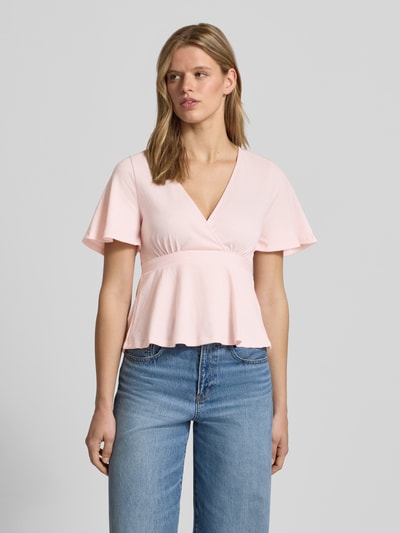 Frauenmodel trägt Regular Fit Bluse in Wickel-Optik Modell 'PELLY' von Only in Rosa mit Strukturmuster, kurzer Ärmel, unifarben, Ganzkörperansicht von vorne.