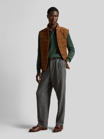 Männermodel trägt Regular Fit Pullover aus reiner Wolle von Polo Ralph Lauren in Dunkelgrün, kombiniert mit brauner Weste und grauer Hose, Ganzkörperansicht von vorne.