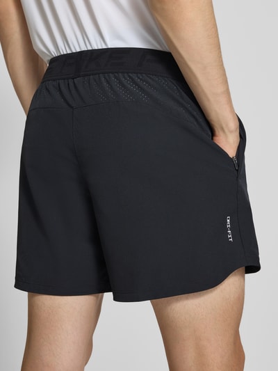 Männermodel trägt Shorts mit Logo und elastischem Bund von NIKE TRAINING im schwarzen Material-Mix mit Stretch-Anteil, Ganzkörperansicht Rückansicht