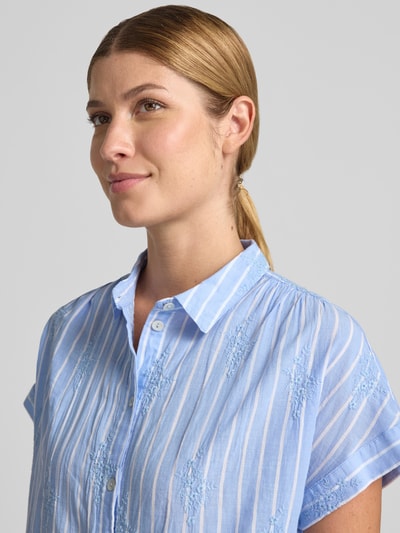 Vrouwenmodel draagt Regular Fit Bluse mit Stitchings und Kappärmeln van Christian Berg Woman in lichtblauw met witte strepen, puur katoen, overhemdkraag, knoopsluiting, kapmouwen, ruglengte maat 36: 65 cm, mouwlengte maat 36: 17 cm, detailopname bovenlichaam.